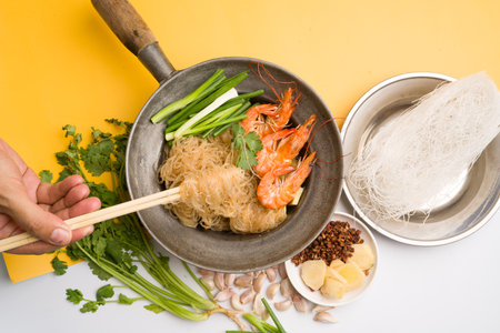 Shrimp with vermicelli in a pan on yellow background