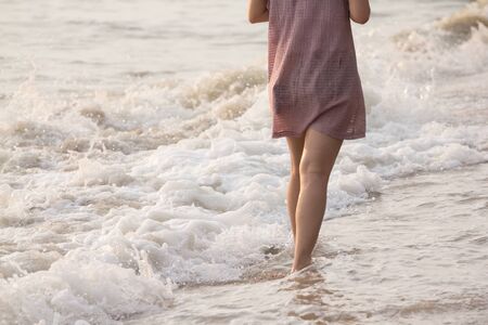 Girl walking on the beach with her bare foot.の写真素材