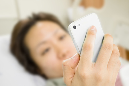 a patient is using smart phone in bedの写真素材
