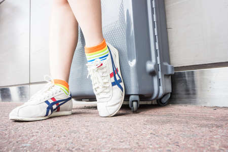 someone in shoes with suitcase is waithing for travelingのeditorial素材