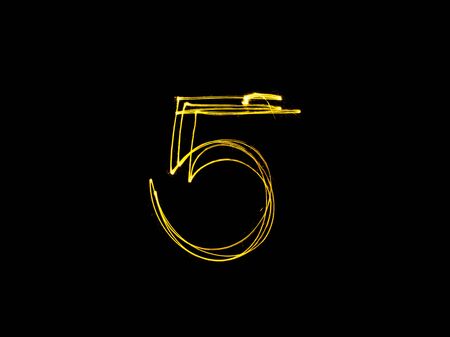 burning sparkler stick and writing sparkling text . number five isolated on black backgroundの写真素材