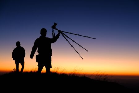 silhouette of photographer show tripod on top of mountain at sunset background, Thailandの写真素材