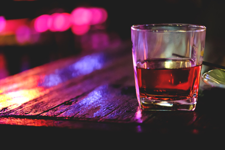 Glass with whiskey on wooden table with a beautiful bokeh. Soft focus, Old cocktail on the bar table with bokeh background.の写真素材