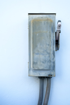 Old and rusty outdoor metal breaker box control, High voltage cabinet, Old dirty electrical box on the wall with cable flexible hoseの写真素材