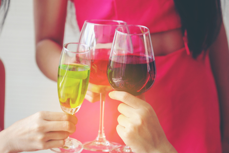 Glasses with cocktails held by happy friends at party, Best friends have new year party celebration, Closeup photo of cheerful girls celebrating a bachelorette party. Hands holding the glasses of champagne and wine making a toast.の写真素材