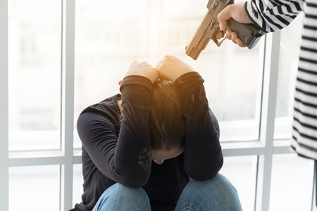 Thief robbery woman with gun ,Dangerous criminal of women in the city. A woman is so scared. thief in balaclava with holding gun, Outlaw bad man  hold a gun pointing the targetの写真素材