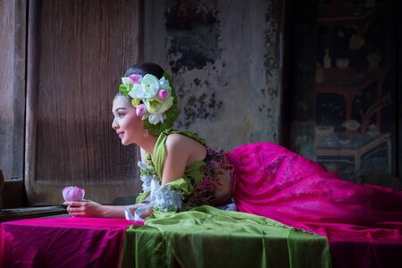Beautiful Asian woman lotus on hand with Thai traditional dress in old templeの写真素材