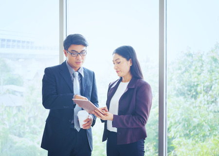 Businesspeople With Digital Tablet In Office, People Meeting Discussion Working Office Concept, Attractive business couple using tablet in their companyの写真素材