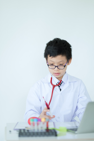 Little cute boy future doctor dressed white holding syringe with injection medical injection in hand, Medicine plastic vaccination equipment with needleの写真素材