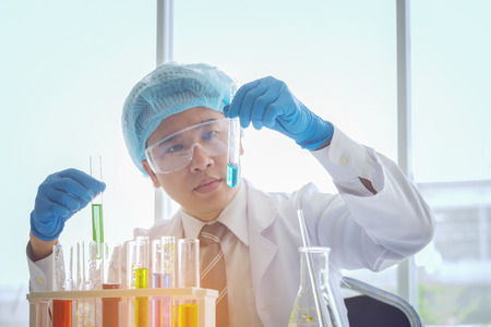 Young male scientist in lab worker making medical research in modern laboratory. Scientist holding...