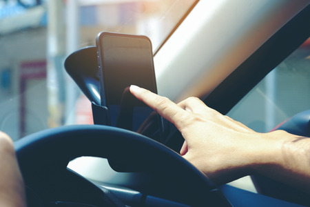 Close-up of hands holding smartphone in the car interior, blank screen for text and content