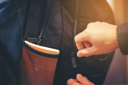 Thief trying to steal the wallet in the backpack, Stealing traveling bag on street in big city, crime robber and steal conceptの写真素材