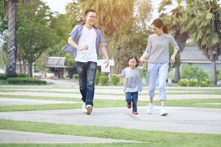 family running through garden at park, Happy family in the park, Mother, father and smilingの写真素材