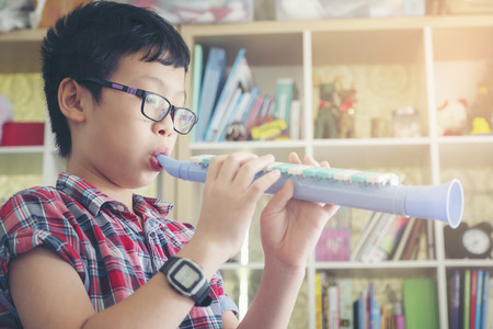 Boy playing the clarinet, trumpet at home, blowing a sweet flute, musicology background, music...