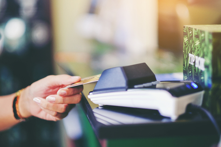 Close up of woman hand holding credit card at the supermarket checkout, she is paying using a credit...