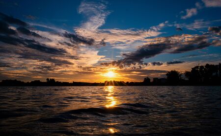 Fiery orange sunset sky. Beautiful sky. sunrise bright colors water reflectの写真素材