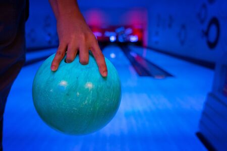 Men's hand holding a blue bowling ball ready to throwの写真素材