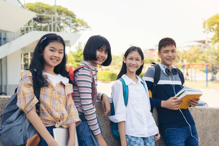 Portrait of School kids with backpacks smiling standing in elementary school hallwayの写真素材