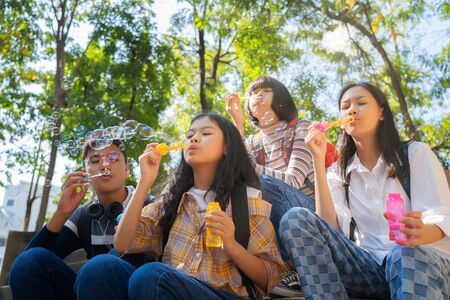 Group of child blowing soap bubbles and having fun in summer park outdoorsの写真素材