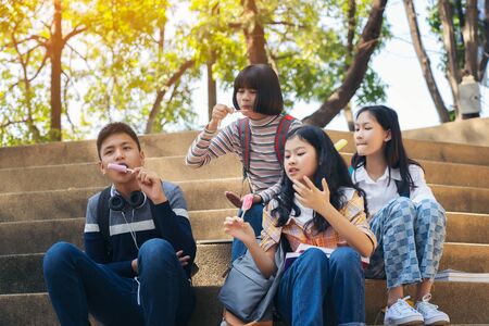 Group of thai students eating ice cream ice-cream sitting at campusの写真素材