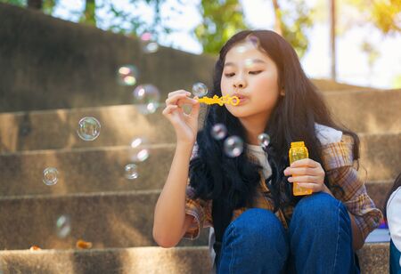 Close up of child blowing soap bubbles and having fun in summer park outdoorsの写真素材