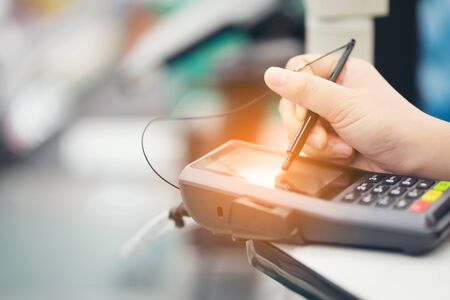 Close-up of consumer's women hand signing on a touch screen of credit card sale transaction receipt machine at supper marketの写真素材