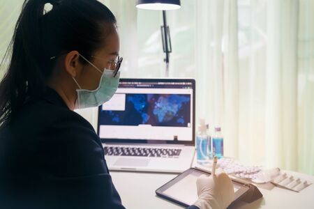 Female Doctor's working on laptop computer, writing prescription notepad with record information on...
