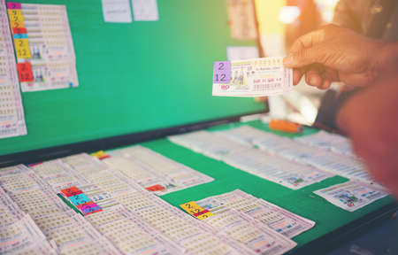BANGKOK, THAILAND - 2020 AUG 12, Man hand holding Thai lottery ready for sale in the market.のeditorial素材