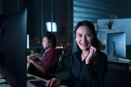 Young Thai Asian customer services care operators working night shift in call center for helping assistance client in workplace at night timeの写真素材