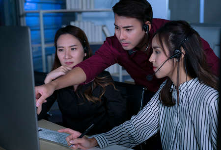 Young Thai Asian customer services care operators working night shift in call center for helping...