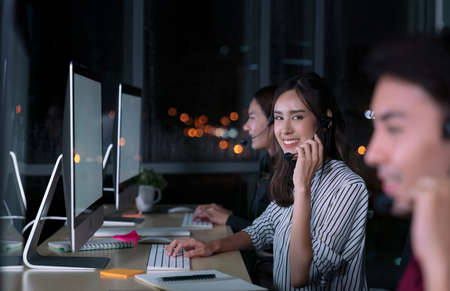 Young Thai Asian customer services care operators working night shift in call center for helping assistance client in workplace at night timeの写真素材