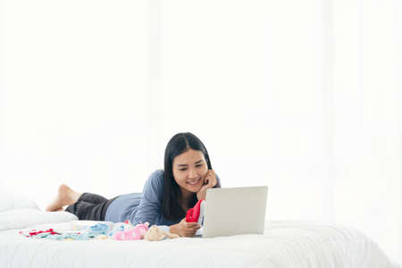 Single mom start working day on a laptop sitting on the bed in the morning. Working from home...