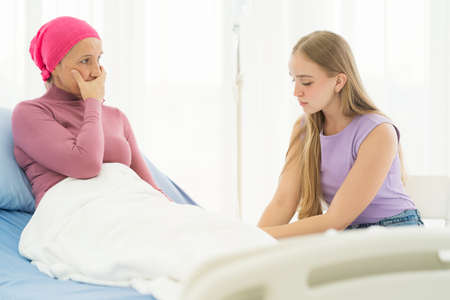 Young adult female cancer patient spending time with hug her daughter on bed at hospital. family support concept.の写真素材