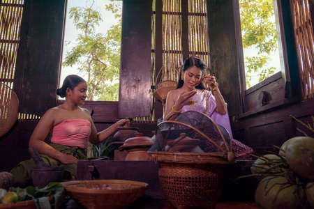 Asian woman wearing Thai dress costume traditional according culture and tradition cooking in the kitchen at the ancient house Ayutthaya, Thailandの写真素材