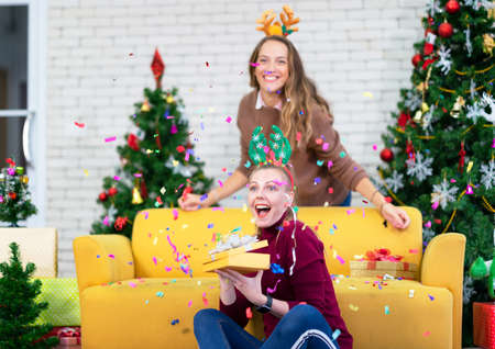 women opening xmas gift box with friend. christmas holiday family concept. celebrate joyfully at...