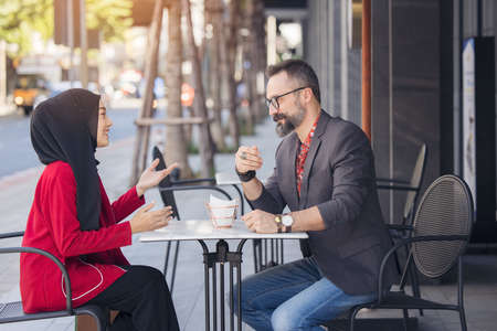 Asian Muslim businesswoman in coffee shop talking to customer or boy friend