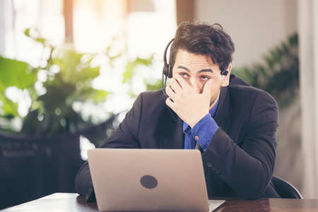 Asian businessman have action with a tired expression between using computer laptop. he cover face with hand upset from work in front of.の写真素材