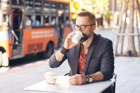 Happy middle age businessman portrait drinking a coffee outdoors in Bangkok, Thailand.の写真素材