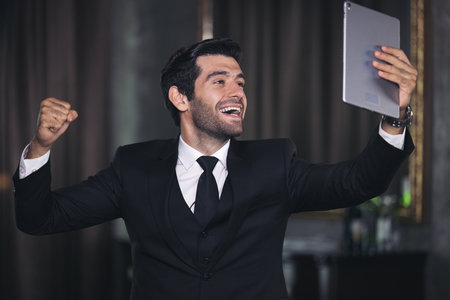 Happy businessman with digital tablet, celebrating success. dark tone