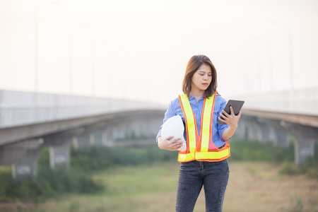 Woman Engineer With White Security Helmet holding tablet Standing On Construction Site