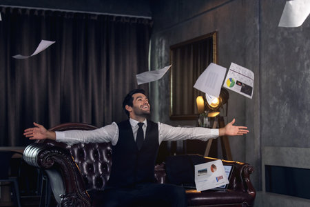 Young man celebrating in office, Businessman cheering at his deskの写真素材