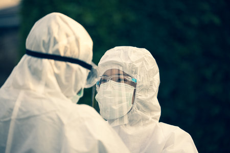 Asian doctor wearing ppe suit and face mask in hospital or outside. Protection from covid-19 and coronavirus pandemicの写真素材