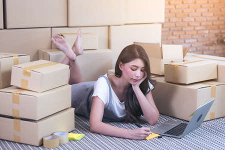 Asian woman packing boxes of parcels in her shopping online business at home.