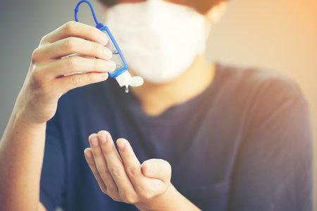 Pandemic Close up Man with Mask using Alcohol Gel Sanitizer Handsの写真素材