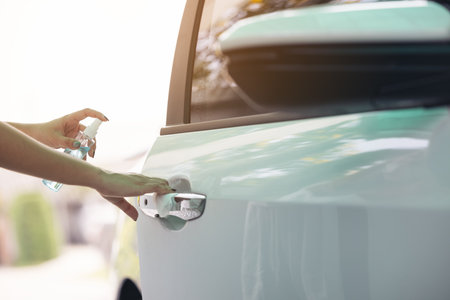 A woman spraying off her car door handle during the COVID-19 scare.の写真素材