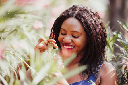 Content Black Woman Smelling Flowers in Park
