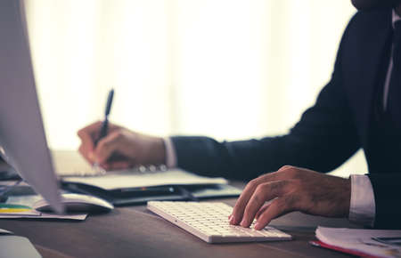 Side view of young businessman using computer while sitting at desk in home office