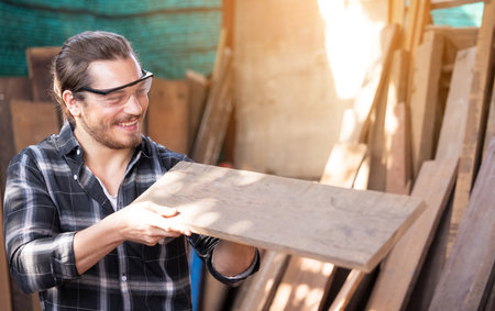 Carpenter work in wood workshop selecting timber for his woddworkの写真素材