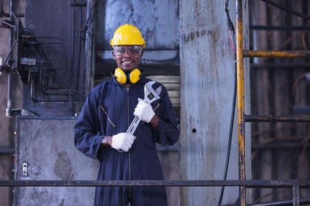 Portrait worker man with yellow helmet and ear protection in factory, Dark toneの写真素材
