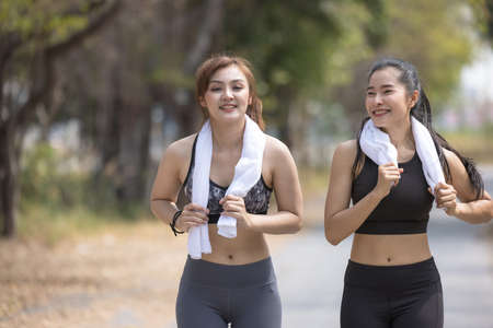 Two Beautiful Female Joggers, girlfriends stretching in parkの写真素材